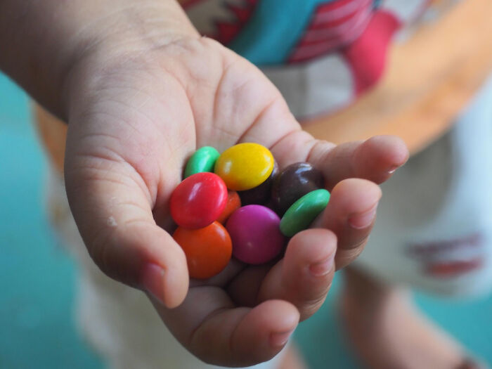 Child holding colorful candy in hand, representing babysitters and bedtime stories with unexpected horror experiences.