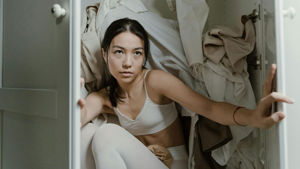 Young babysitter in white clothes hiding in a closet, experiencing a terrifying and unsettling horror moment.