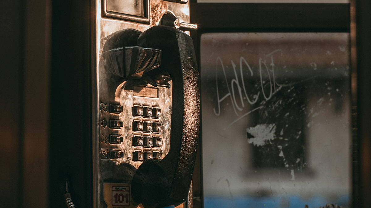 Old payphone with worn buttons and handset in dim lighting, evoking a terrifying true story atmosphere.