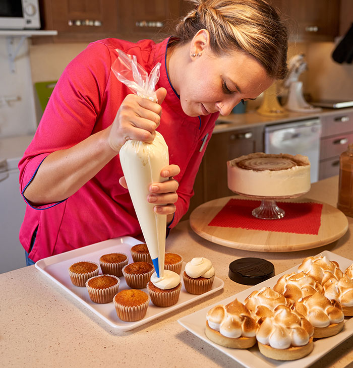 Mom carefully decorating cupcakes in kitchen after hours of baking for son’s birthday celebration and school reaction. Mom carefully decorating cupcakes in kitchen after hours of baking for son’s birthday celebration and school reaction.