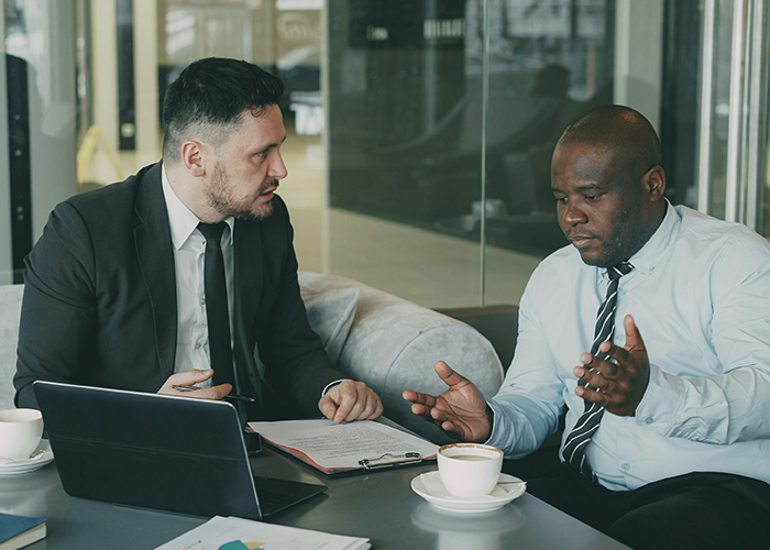 Two businessmen in a serious discussion with laptop and documents, illustrating server down during business hours and malicious compliance. Two businessmen in a serious discussion with laptop and documents, illustrating server down during business hours and malicious compliance.