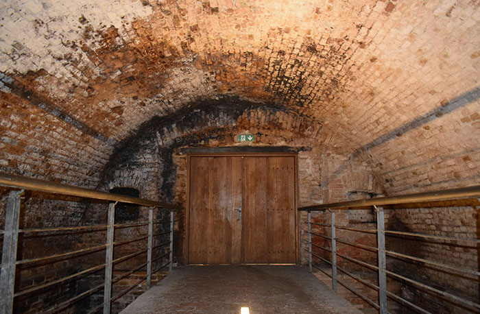 Dark brick tunnel with wooden door at the end, representing school gossip secrets exposed as facts.