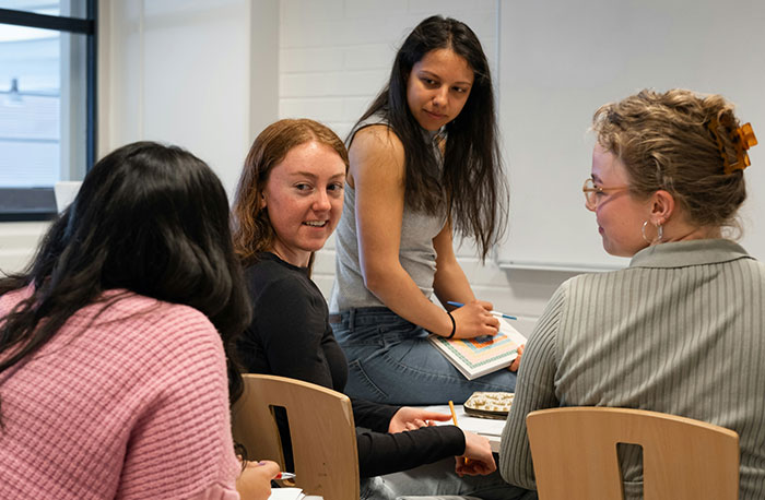 Four students sitting in a classroom engaged in conversation, illustrating school gossip turned out to be facts.