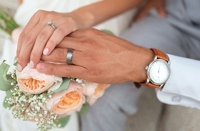 Hands with wedding rings resting on a bouquet of flowers, symbolizing moments when school gossip turned out to be facts.