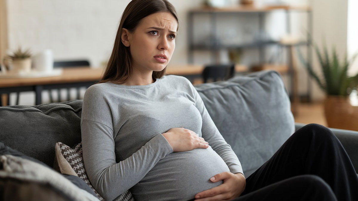 Pregnant woman looking distressed on a couch, highlighting risks of anaphylaxis from ignoring no-peanut rules at home.