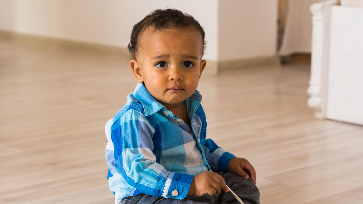 Toddler sitting alone on floor indoors, looking sad, representing single mom abandoning toddler and parents restarting life.