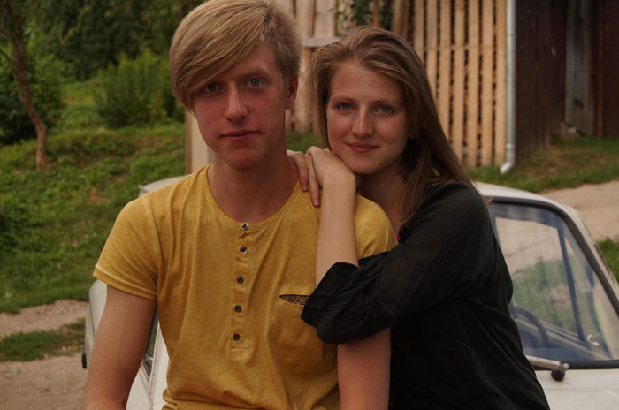 Young couple sitting together outdoors near a car, portraying sister boyfriend relationship drama with a thoughtful mood. Young couple sitting together outdoors near a car, portraying sister boyfriend relationship drama with a thoughtful mood.