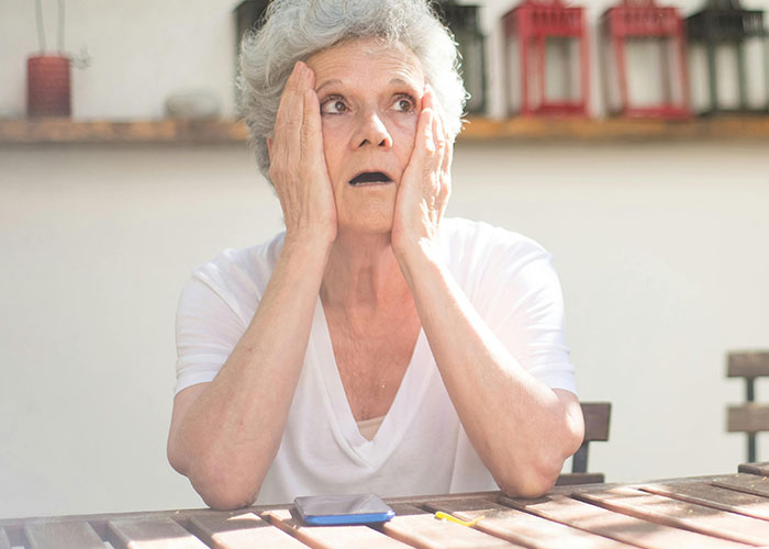 Elderly woman with a shocked expression sitting at a wooden table, reflecting on what husband thinks of her body. Elderly woman with a shocked expression sitting at a wooden table, reflecting on what husband thinks of her body.