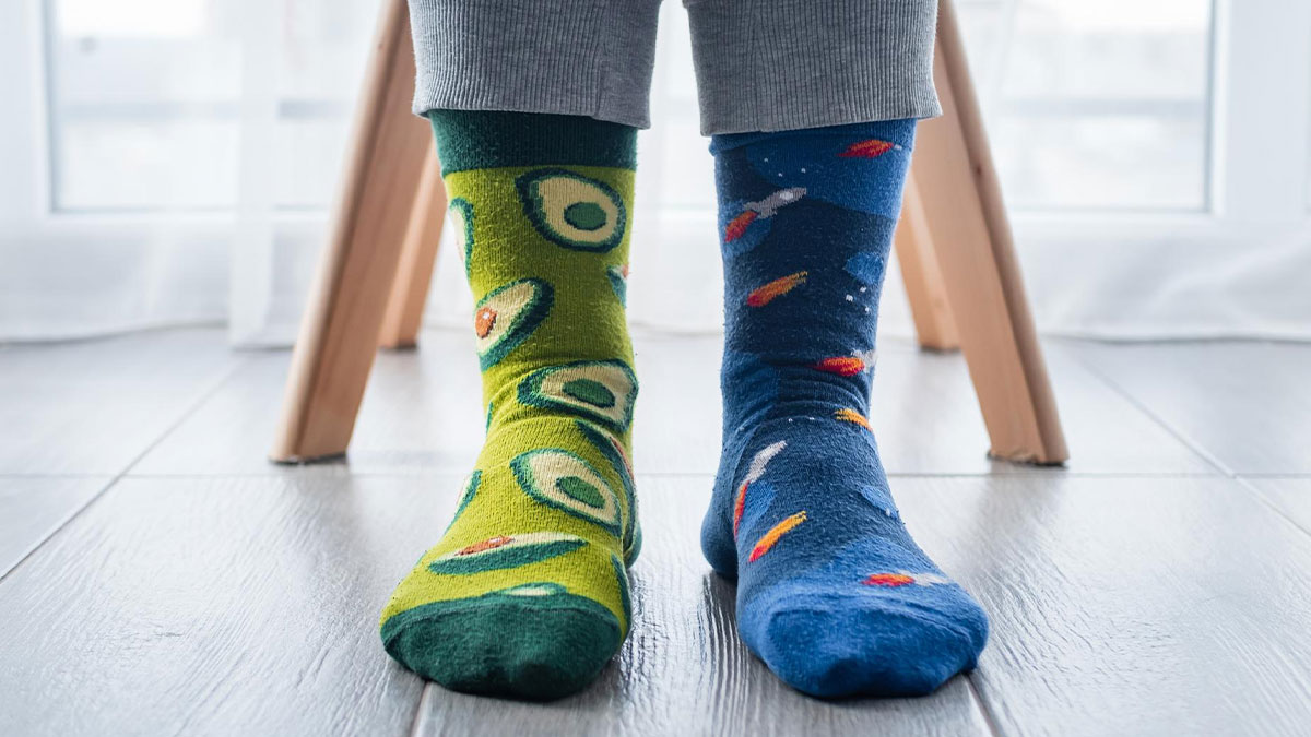Person wearing colorful socks with avocado and rocket patterns, highlighting workplace harassment over clothing choices.