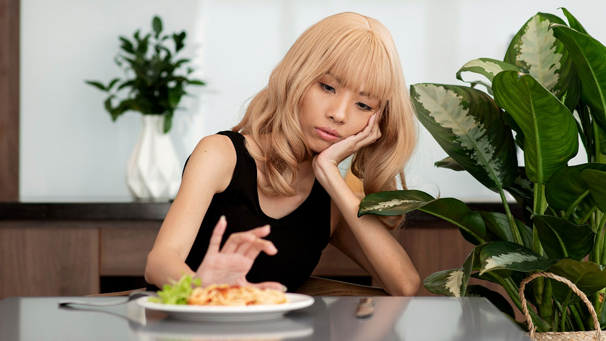 Young woman looking sick and upset while avoiding parents food at the dining table in a home setting