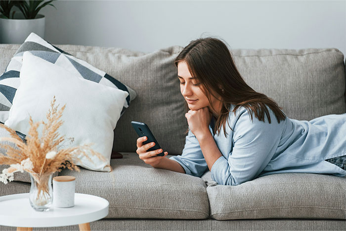 Woman lying on a couch looking at her phone, representing crazy and unhinged ways people found out their partner was cheating.