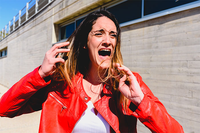 Woman in a red jacket showing shock and disbelief outside, illustrating reactions to finding out a partner was cheating.