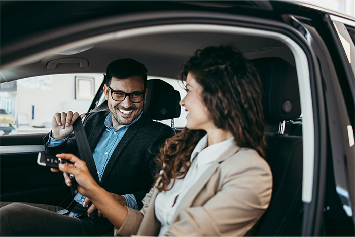A smiling man and woman sitting in a car, symbolizing unexpected moments people found out their partner was cheating.