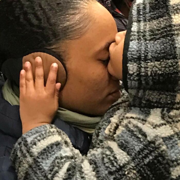Woman on New York subway with child resting hand on her ear, illustrating people carrying cute and funny things in their hands.