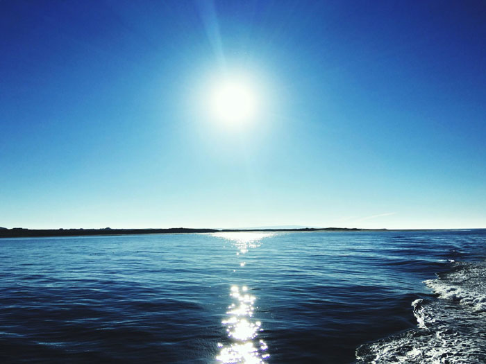 Bright sun shining over calm blue ocean with clear sky reflecting the time when the sun turned blue mystery. Bright sun shining over calm blue ocean with clear sky reflecting the time when the sun turned blue mystery.