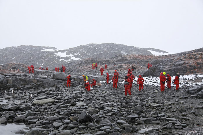 Researchers in red suits exploring rocky icy terrain as part of the 1831 mystery involving the sun turning blue. Researchers in red suits exploring rocky icy terrain as part of the 1831 mystery involving the sun turning blue.