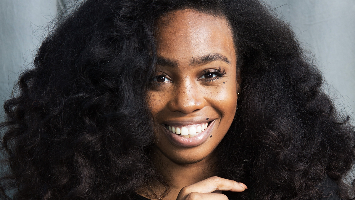Close-up of a smiling woman with natural hair showcasing confidence after cosmetic transformation confessions.