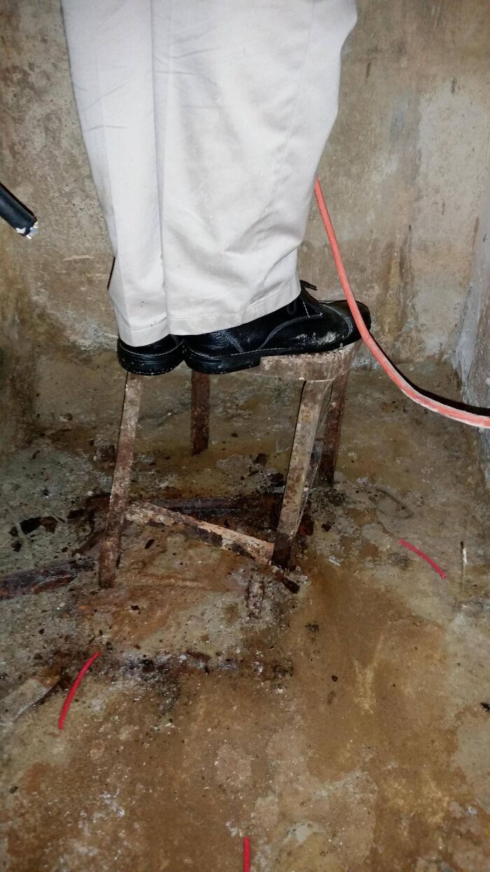 Person wearing black shoes standing on a rusty stool inside a dirty underground space exploring beneath our feet.