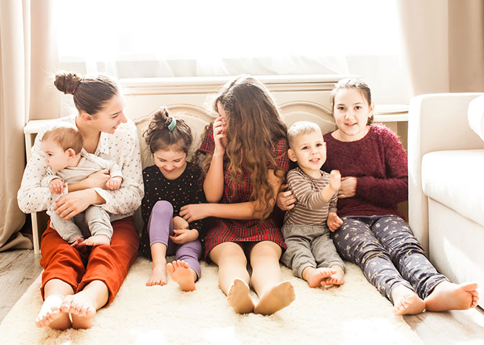 Siblings sitting together on the floor, taking care of younger children, showing support and family bonding at home. Siblings sitting together on the floor, taking care of younger children, showing support and family bonding at home.
