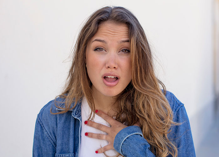 Young woman in denim jacket shows shocked expression, illustrating siblings refusing support while taking care of mother. Young woman in denim jacket shows shocked expression, illustrating siblings refusing support while taking care of mother.