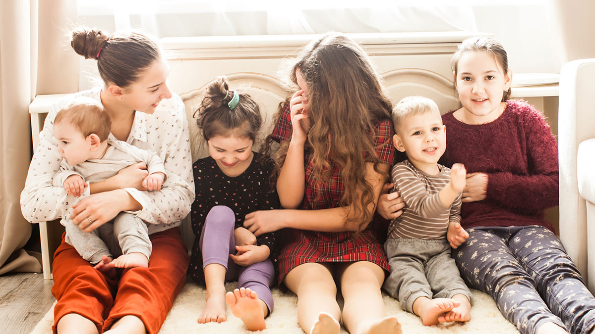 Siblings sitting together at home, one taking care of a baby, reflecting the theme of refusing support from mother.