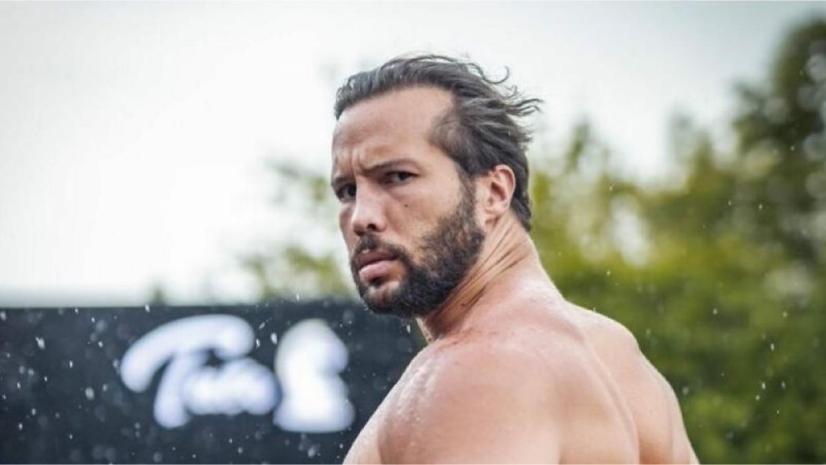 Tristan Tate looking over his shoulder outdoors with wet hair and a serious expression, legal turmoil impacting net worth.