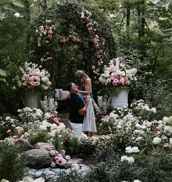 Couple sharing romantic moment in garden surrounded by flowers, illustrating mom telling 6YO daughter about Taylor Swift wedding. Couple sharing romantic moment in garden surrounded by flowers, illustrating mom telling 6YO daughter about Taylor Swift wedding.