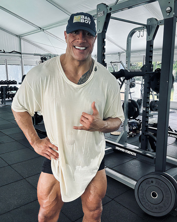 Dwayne Johnson in gym wearing a loose white shirt and black cap, showing his slim look after recent health concerns. Dwayne Johnson in gym wearing a loose white shirt and black cap, showing his slim look after recent health concerns.