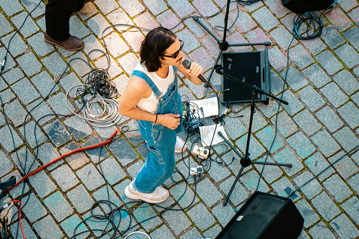 Street performer singing with microphone and equipment, showing things that look awesome in movies but are terrible in real life.