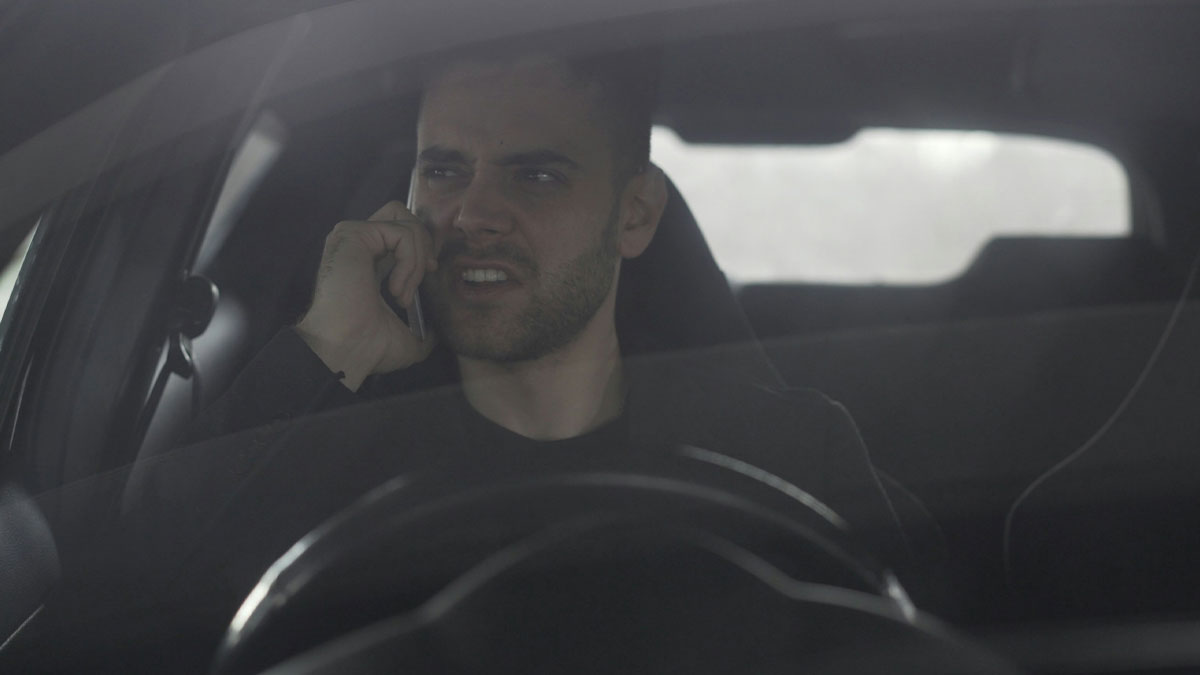 Man in dark jacket making a tense phone call inside a car, illustrating things men do that affect women feeling safe or threatened