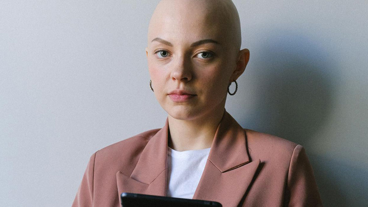 Young bald woman in a blazer, holding a tablet, symbolizing things women are not allowed to do versus men freely
