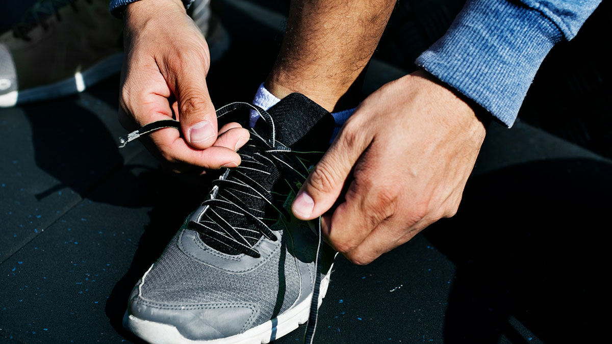 Close-up of a grown adult tying shoelaces on a sneaker, highlighting everyday things that humble adults.