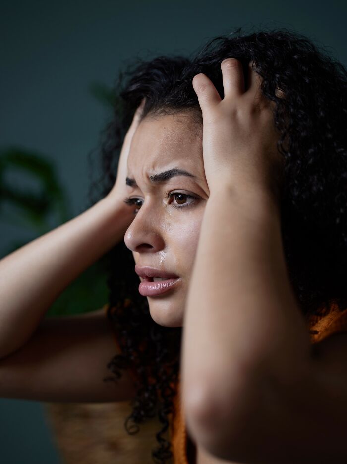 Worried woman holding her head, upset and emotional, illustrating dumbest and out of touch things people have been told.