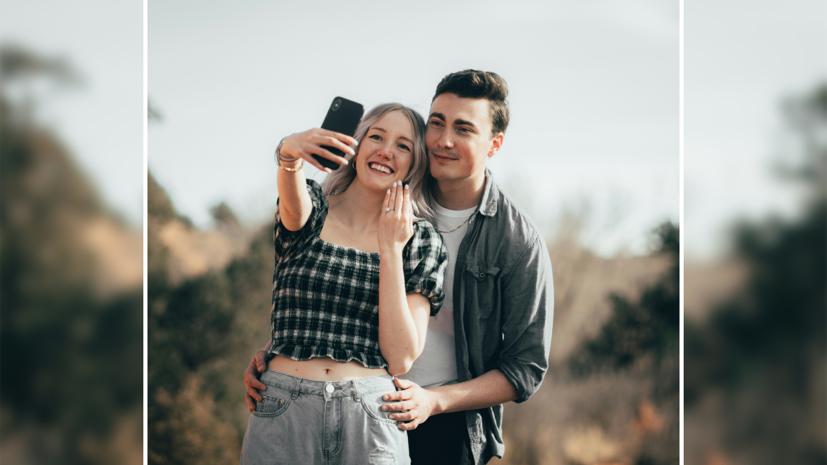 Young couple taking a selfie outdoors, showing happy faces while exploring red flags in a relationship dynamics.