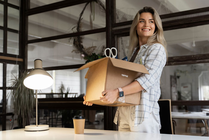 Smiling employee carrying a box with personal items, leaving office ahead of disciplinary hearing, surprising toxic bosses. Smiling employee carrying a box with personal items, leaving office ahead of disciplinary hearing, surprising toxic bosses.
