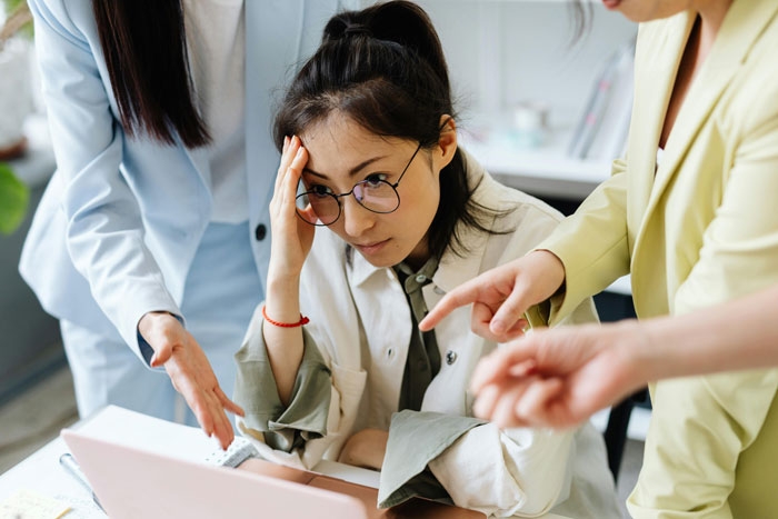 Stressed employee facing disciplinary hearing while her toxic bosses point fingers in a tense office setting. Stressed employee facing disciplinary hearing while her toxic bosses point fingers in a tense office setting.