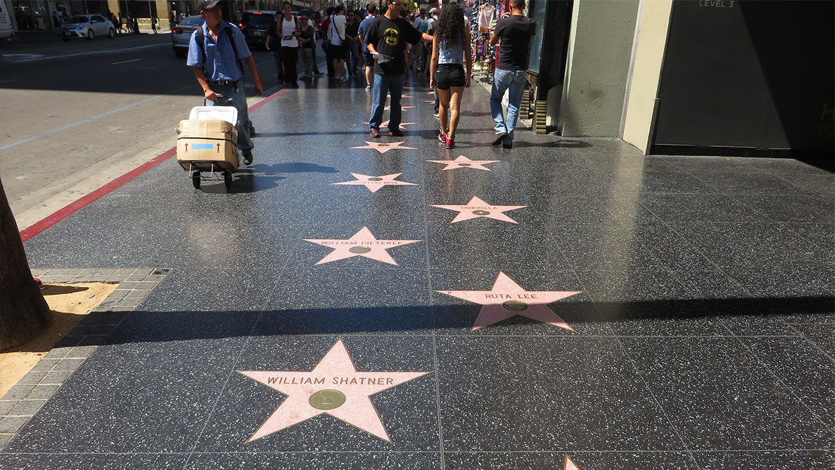 Hollywood Walk of Fame stars on a busy sidewalk with tourists, a popular travel destination seen in person.