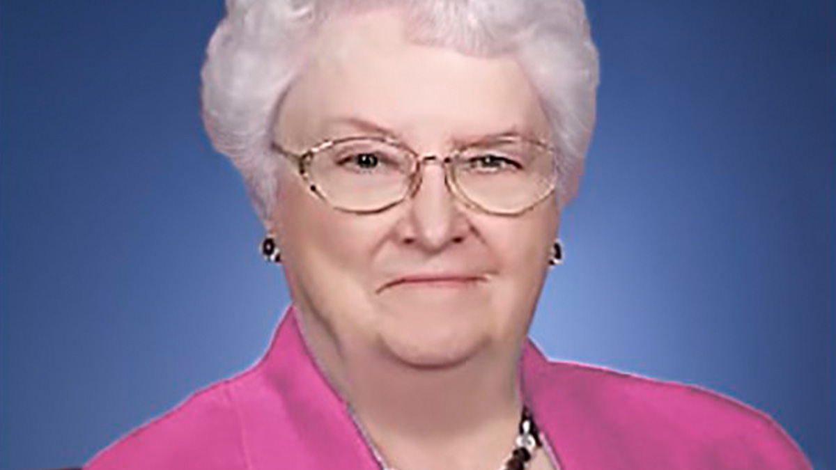 Elderly woman with white hair and glasses wearing a pink blouse, known as the internetu2019s funniest grandma with sharp humor.