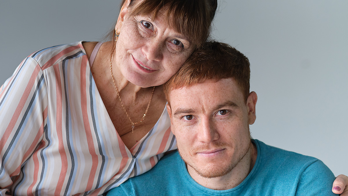Affectionate middle-aged woman and young man posing closely, illustrating boyfriend being affectionate with his mom concept.
