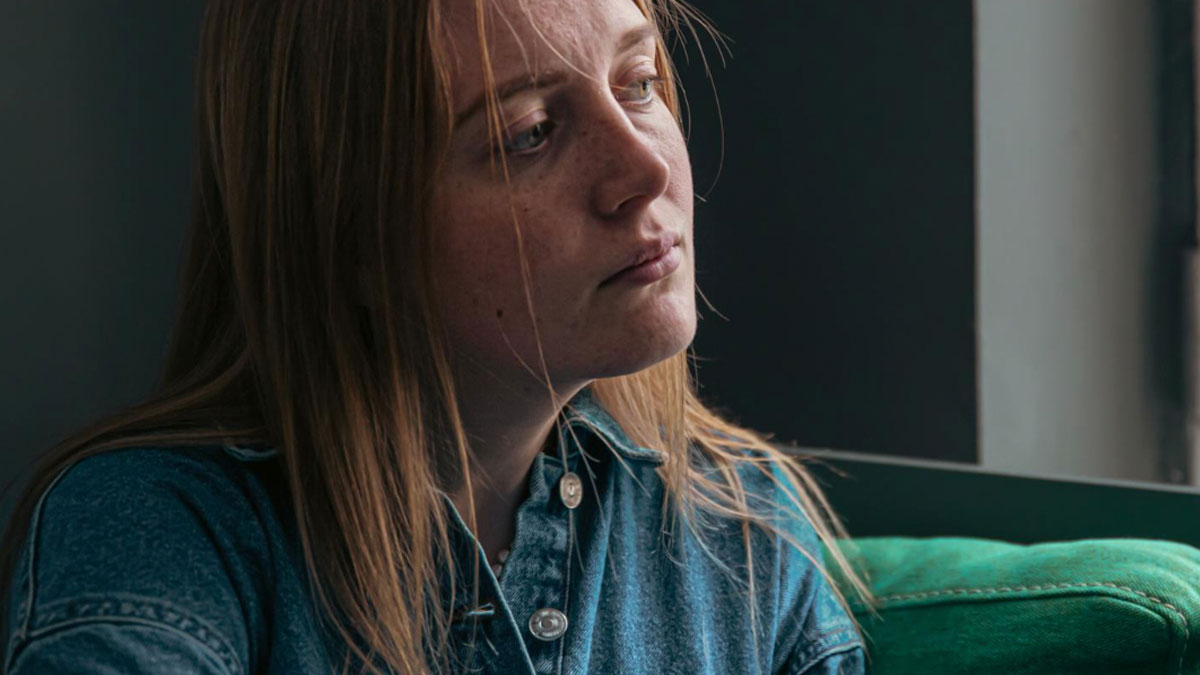 Teenage daughter heartbroken and lonely, staring away while parents prefer watching TV all day instead of spending time.