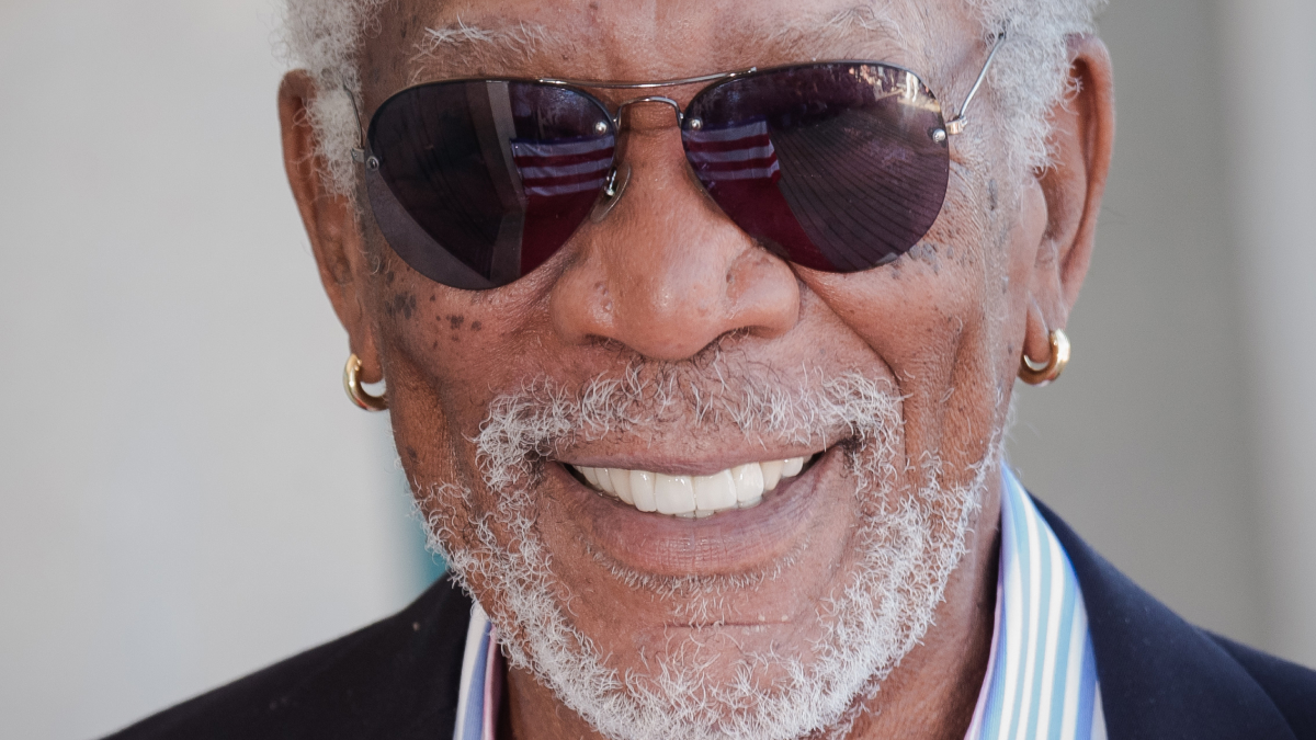 Elderly man with white beard wearing sunglasses and showing bright veneers before and after smile makeover.