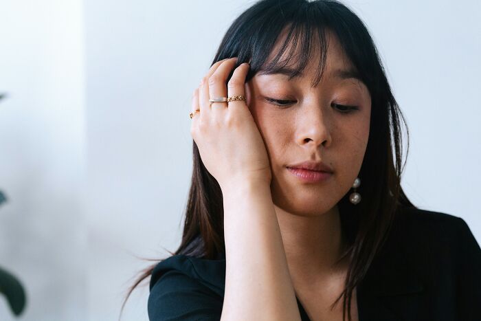 Young woman with black hair resting her head on her hand, reflecting on things people would never admit in real life.