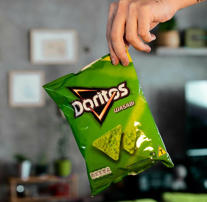 Hand holding a green bag of Doritos wasabi chips, representing overhyped products people say to stop buying.