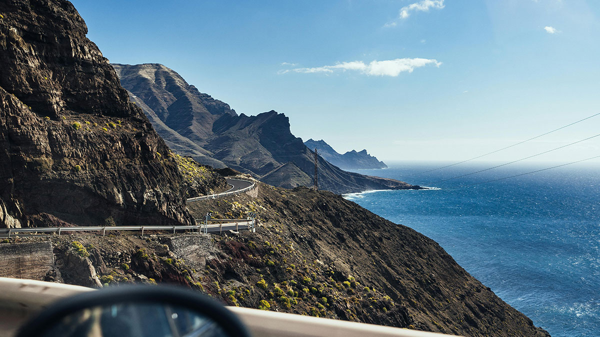Coastal mountain road winding along cliffs with ocean view, illustrating incredible coincidences in nature and landscape.