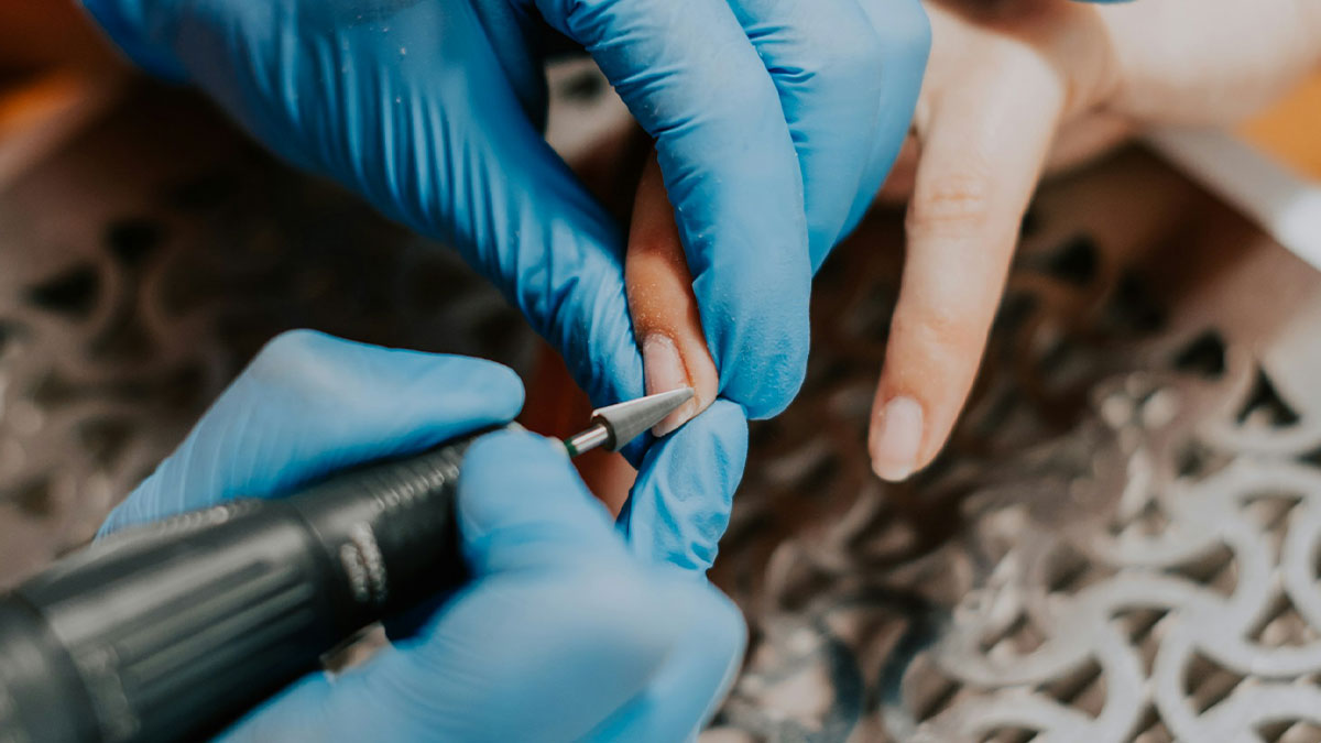 Close-up of a person filing fingernails with an electric nail drill, highlighting unusual ways people died keyword concept.