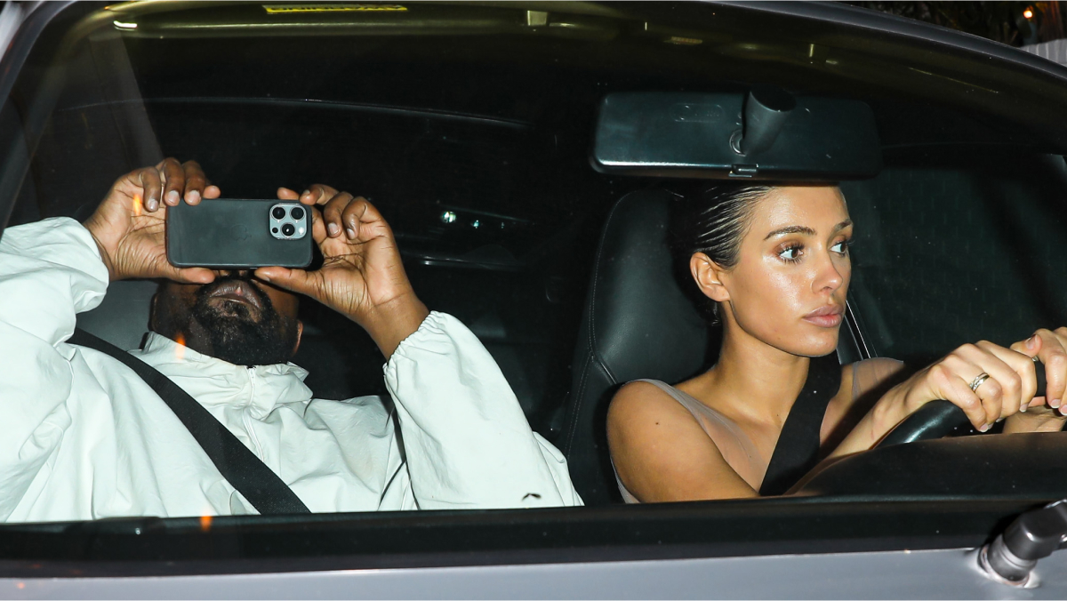 Bianca Censori driving a car at night with a passenger capturing photos, highlighting her role in Westu2019s empire growth.