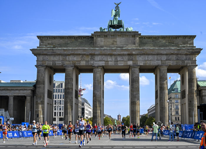 Runners participating in the Berlin Marathon passing under the Brandenburg Gate during the race event. Runners participating in the Berlin Marathon passing under the Brandenburg Gate during the race event.