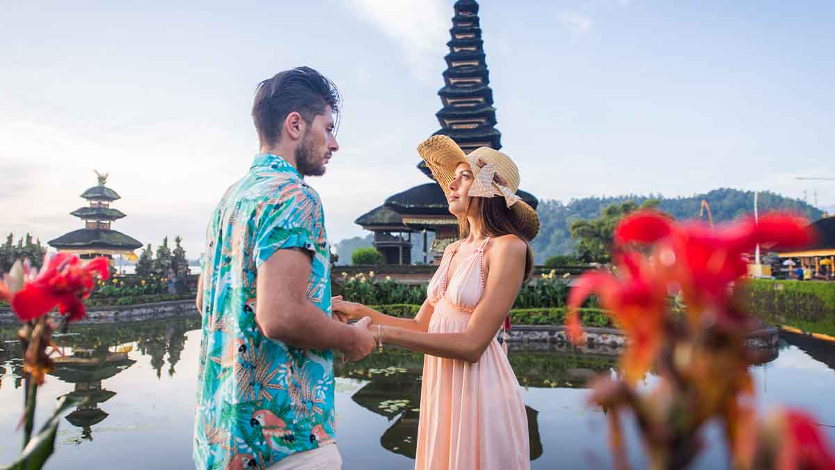 Couple on honeymoon holding hands at a temple with scenic background, illustrating honeymoon travel and finances.