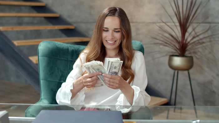Woman counting money at a desk, smiling confidently, illustrating wife turned mean once got money concept. Woman counting money at a desk, smiling confidently, illustrating wife turned mean once got money concept.