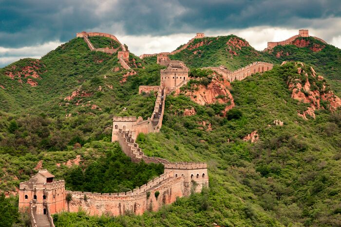 Great Wall of China winding over green hills under a cloudy sky, illustrating so-called facts about history myths.